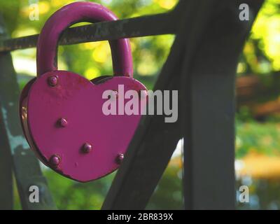 Old rusty en forme de coeur rose sur un pont en acier cadenas, gros plan, arrière-plan conceptuel de l'amour Banque D'Images