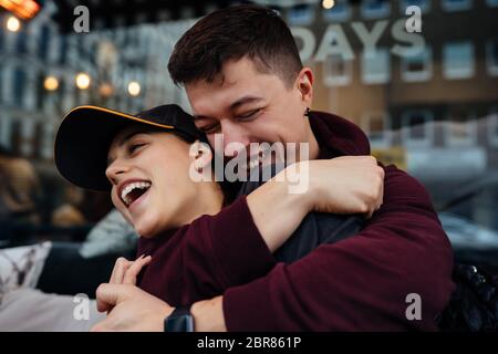 Guy et une fille s'embrasent à une table dans un café extérieur. Banque D'Images