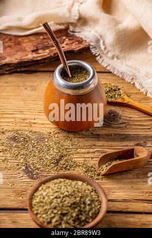 Les feuilles de maté et de thé mate en calebasse avec bombilla sur un fond de bois Banque D'Images