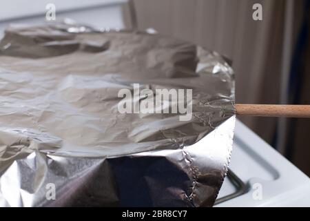 Les restes dans une casserole couverte de papier aluminium et le mélange d'une cuillère en bois qui sort Banque D'Images