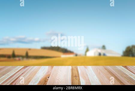 Plateau de table en bois vide prêt pour le montage de produit avec ferme dans un arrière-plan flou de campagne. Banque D'Images