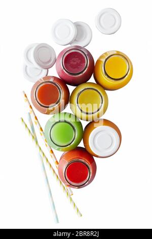 Vue aérienne sur un assortiment de bouteilles de jus de couleurs différentes à côté de white caps et des pailles isolées sur fond blanc Banque D'Images