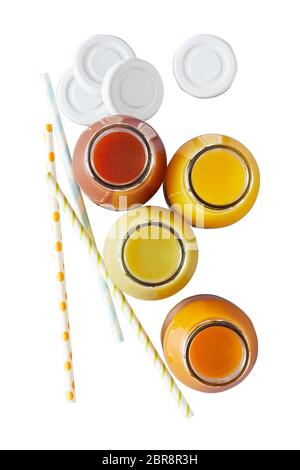 Quatre pots de verre rempli de jus d'orange-jaune et rouge à côté de pailles à rayures et blanc sur blanc Banque D'Images