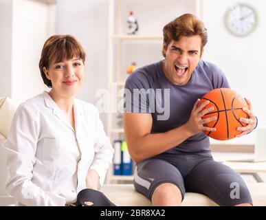 Le beau joueur de basket-ball féminin en visite médecin traumatologist Banque D'Images