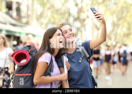 Deux heureux backpackers en tenant vos autoportraits avec un téléphone intelligent dans la rue en vacances Banque D'Images