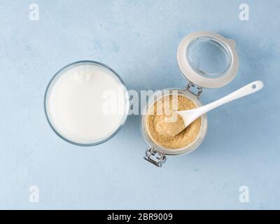 La levure alimentaire et le lait. Levure inactive nutritionnel en pot et verre de lait sur la table bleue. Copier l'espace. Vue d'en haut. La levure alimentaire est vegetaria Banque D'Images