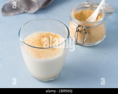 La levure alimentaire et le lait. Levure inactive nutritionnel en pot et verre de lait sur la table bleue. Copier l'espace. La levure alimentaire est végétarien superfoo Banque D'Images