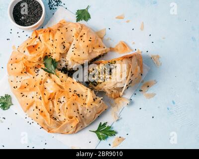 Spanakopita tarte grecque sur un papier blanc sur fond bleu. Idées et recettes pour les végétariens ou végétaliens Spanakopita Tarte aux épinards de pâte fillo Banque D'Images