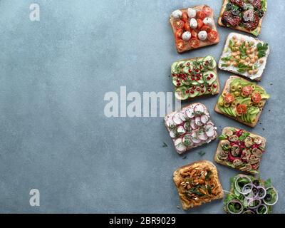 Assortiment de sandwichs végétaliens sur fond noir en gris. Définir différents smorrebrod végétarien. Vue de dessus ou de télévision. L'espace de copie pour le texte. Banque D'Images