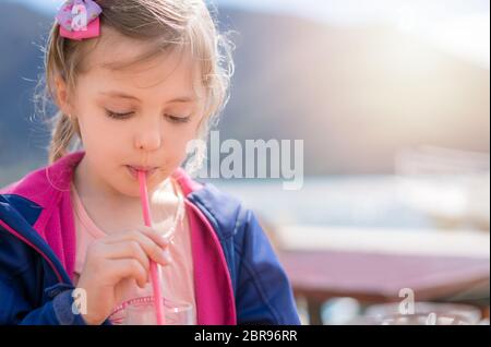 Cute little woman boire du jus de fruits à travers la paille en été Banque D'Images