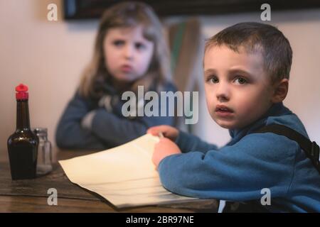 Des enfants assis à la table de restaurant en attente d'un repas pour être servi Banque D'Images
