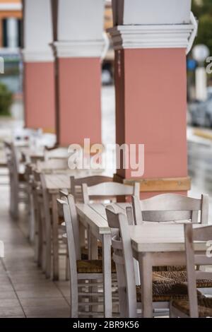 Rangée de chaises en bois blanc et des tables à l'extérieur restaurant sur un jour d'été pluvieux, Zante, Grèce Banque D'Images