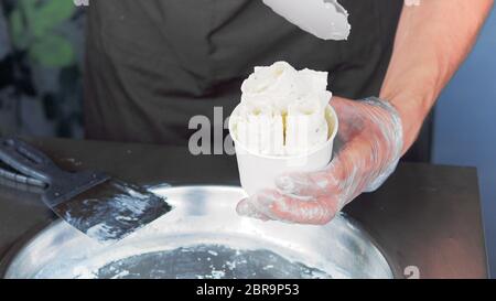 Incorporer la crème glacée frite-rouleaux à geler la casserole. Faire de la crème glacée laminées, part de la création d'un dessert. La crème glacée frite machine avec steel pan réfrigérés. Banque D'Images