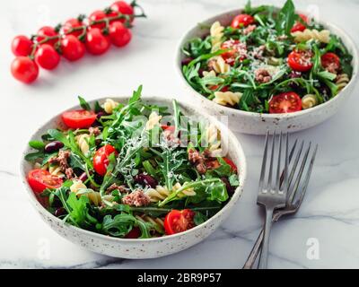 Salade de thon, tomates, roquette, haricot rouge, des pâtes. Idée et recette pour un déjeuner ou dîner. Deux bols à salades chaudes sur la table de marbre. Banque D'Images