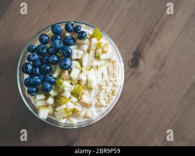 Vue de dessus du bol avec millet bouillie sur fond de table en bois. Porridge de millet bio avec Blueberry et de poire, l'espace de copie pour le texte. Soft focus, sh Banque D'Images