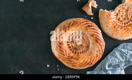 Frais savoureux pain tandoori sur table noire. Deux pains plats tandoori cake avec des morceaux et des miettes sur pierre sombre arrière-plan. Repas asiatique et de l'alimentation. C Banque D'Images