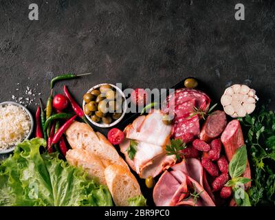 L'antipasto set plateau sur fond noir en noir. La viande fumée à froid avec plaque,saucisse jambon tranché, bacon, olives, pain, fromage et d'herbes. Apéritif var Banque D'Images