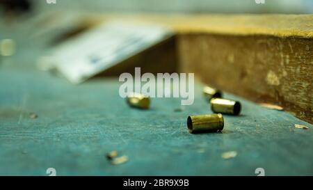 Balle de pistolet vide sur une table en bois dans un champ de tir. Extreme close up et selective focus avec arrière-plan flou. Banque D'Images