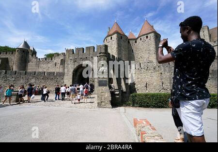 Un visiteur prenant des photos de la porte de Narbonne l'entrée principale de la ville fortifiée historique de Carcassonne.Aude.Occitanie.France Banque D'Images