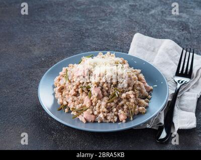 Le sarrasin cru risotto à la viande de poulet et fromage parmesan romarin servi en gris sur fond noir de la plaque de ciment. Des plats sans gluten et de sarrasin recette Banque D'Images