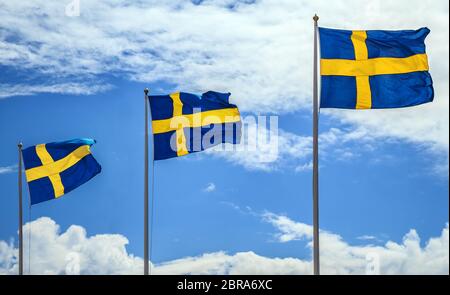 Les drapeaux nationaux de la Suède sur fond de ciel bleu avec des nuages. Banque D'Images