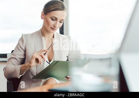 Belle femme d'affaires lisant un dossier dans son bureau par la fenêtre Banque D'Images