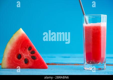 Un morceau de melon et de pastèque smoothie,jus jus dans un verre transparent sur un fond de bois bleu Banque D'Images