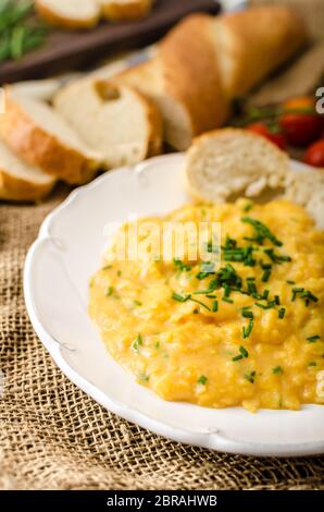 French style oeufs brouillés à la ciboulette avec baquette française et mini-tomates Banque D'Images