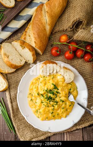 French style oeufs brouillés à la ciboulette avec baquette française et mini-tomates Banque D'Images