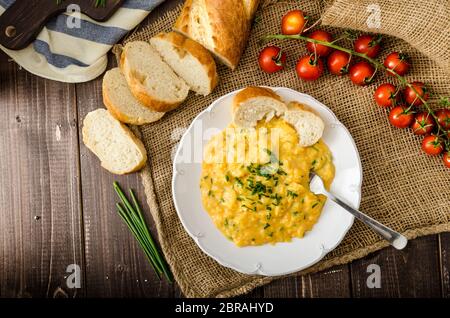 French style oeufs brouillés à la ciboulette avec baquette française et mini-tomates Banque D'Images