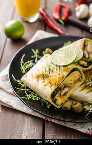 Petit-déjeuner burrito avec œufs, cheddar, microgreens, olives et champignons grillés Banque D'Images