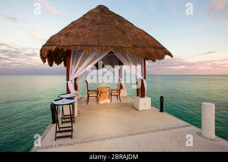 Table pour deux sur les quais au crépuscule à Puerto Morelos, Quintana Roo, Mexique. Banque D'Images