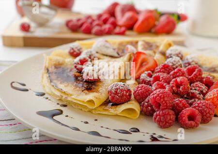 Des crêpes faites maison avec la réduction de vinaigre balsamique et de fruits frais, fraises et framboises Banque D'Images