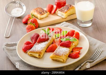 Blintzes - crêpes au fromage riccota rempli et creame fraîche avec des fruits frais et de menthe Banque D'Images