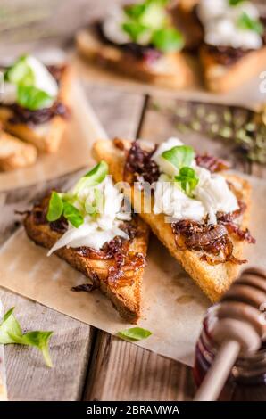 Toast rustique avec oignon caramélisé, fromage de chèvre, ail et herbes Banque D'Images