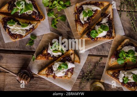 Toast rustique avec oignon caramélisé, fromage de chèvre, ail et herbes Banque D'Images