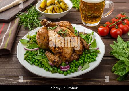 Poulet grillé bio bio, pommes de terre, d'Herbes et légumes de printemps avec, avec de la bière Banque D'Images
