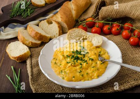 French style oeufs brouillés à la ciboulette avec baquette française et mini-tomates Banque D'Images