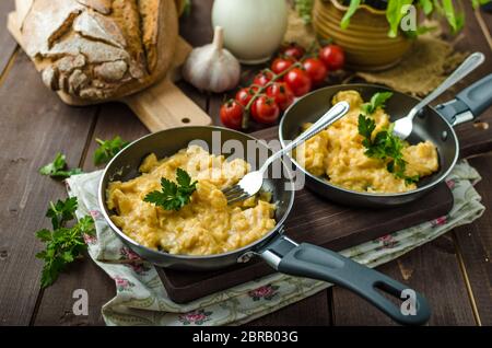 Oeufs brouillés aux fines herbes et du pain fait maison, sur deux poêles à frire Banque D'Images