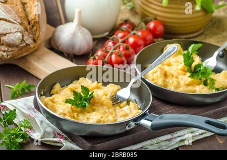 Oeufs brouillés aux fines herbes et du pain fait maison, sur deux poêles à frire Banque D'Images