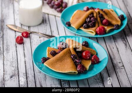 Des crêpes faites maison avec des baies congelées, garni de sucre, bois rustique, vintage photography Banque D'Images