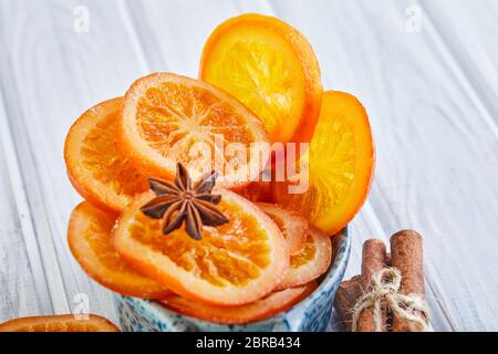 Tranches d'oranges séchées ou de mandarines à l'anis et à la cannelle dans un bol bleu sur fond clair. Végétarisme et alimentation saine. Copier l'espace. Banque D'Images