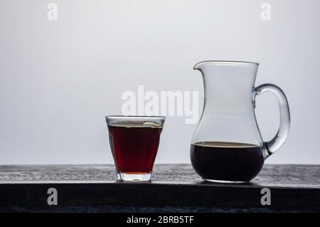 Une cruche et un verre de café noir sur une table en bois voile de fond. Banque D'Images