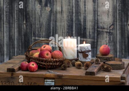 style rustique encore vie avec bougies, pommes et cônes de pin sur une vieille caisse en bois Banque D'Images