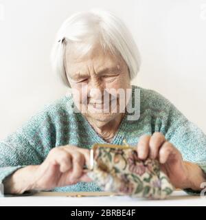 Personnes âgées gaies 96 ans woman sitting at table à la maison heureux avec elle dans son portefeuille d'épargne-retraite après le paiement des factures. L'épargne-retraite un Banque D'Images