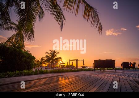 Belle piscine et Ciel de coucher du soleil. Paysage plage tropicale luxueuse, chaises longues et transats et une réflexion de l'eau. Banque D'Images
