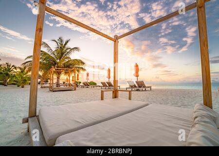 Paysage de plage d'été. Concept de vacances de luxe, bannière de voyage d'été. Paysage panoramique de plage au coucher du soleil, deux chaises longues, parasols Banque D'Images