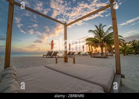 Paysage de plage d'été. Concept de vacances de luxe, bannière de voyage d'été. Paysage panoramique de plage au coucher du soleil, deux chaises longues, parasols Banque D'Images