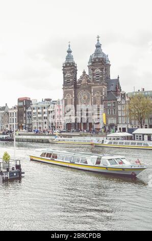 Amsterdam, pays-Bas - 27 avril 2019 : Canal au centre de la capitale néerlandaise. Bateau sur le canal. Centre ville en arrière-plan. Ciel couvert. Photo verticale. Banque D'Images