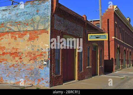 Old Blacksmith Building avec ciel bleu à Sterling Kansas USA qui est lumineux et coloré avec un trottoir. Banque D'Images